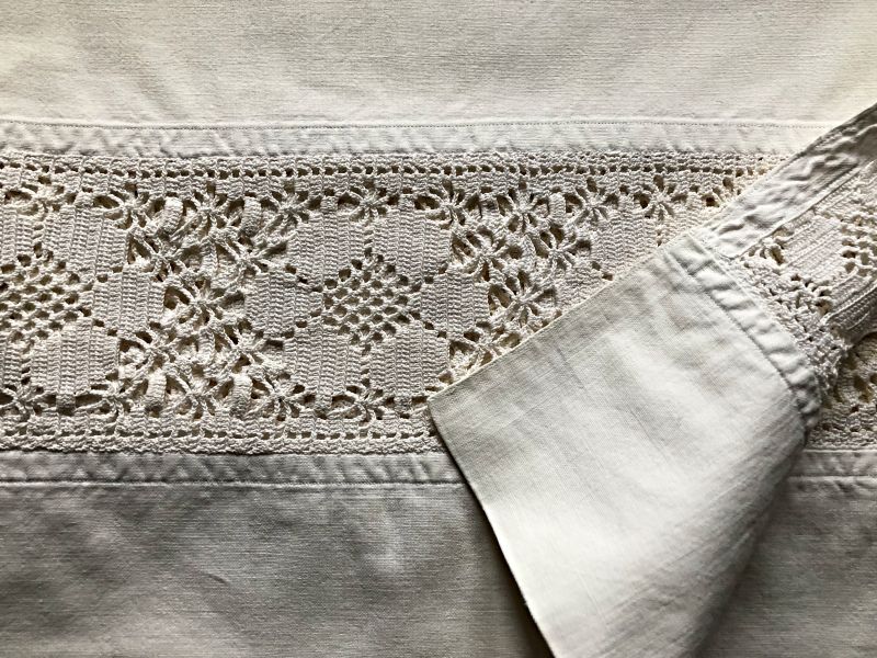 A crochet lace, dated circa 1900, was used as an inset decoration on a cotton bedsheet in the same manner as linen bobbin laces had embellished the linen bedsheets a hundred years earlier. The handcrafted cotton crochet lace was carefully machine-stitched onto the plain cotton bedsheet. (Private ownership). Photo: Viveka Hansen, The IK Foundation.