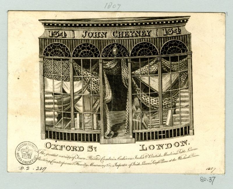 A third example of trade-cards showing display windows is illustrated from a small drapery shop in 1807 –  who sold a large selection of printed muslins, linens etc at Oxford Street in London. Courtesy  of: © Trustees of the British Museum, Trade cards, Banks 80.37. (Collection online).